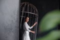 Reflection in the mirror of bride in cage on gray concrete background. Patriarchal marriage concept