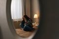 Reflection on mirror of desperate young woman crying suffering from depression sitting on bed in bedroom on background Royalty Free Stock Photo