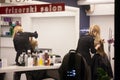 reflection in mirror of a hairdresser, woman, cutting the hair of a female client in a hairdressing salon wearing facemask Royalty Free Stock Photo