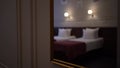 Reflection in the mirror of made beds with white pillows, sconces on the wall. Blurred background with copy space