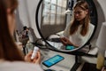 Reflection in mirror of stressed teenage girl looking at bottle of pills in her hands Royalty Free Stock Photo