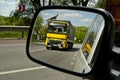 Reflection in the mirror yellow truck passing car.