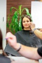 Reflection in the mirror of the young caucasian woman sitting and receiving haircut by male hairdresser at hairdresser Royalty Free Stock Photo