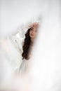 Reflection in the mirror of young pretty brunette girl with incredible makeup in white summer dress.