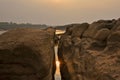 Reflection of morning sun and the river in the broken stone cliff