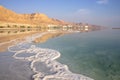 Reflection of mountains, hotels and palm trees in the water of the Dead Sea with salt formations Royalty Free Stock Photo