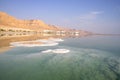 Reflection of mountains, hotels and palm trees in the water of the Dead Sea with salt formations Royalty Free Stock Photo