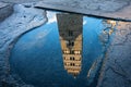 Reflection of Pistoia Cathedral bell tower in the puddle in Tuscany, Italy