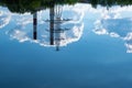 Reflection of a power line, two tall pipes and dark cumulus clouds in the water Royalty Free Stock Photo