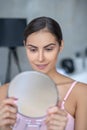 Pretty woman in pink lingerie holding a round mirror