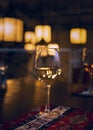 Reflection of the restaurantÃ¢â¬â¢s light rays and the surrounding space in a glass of white wine standing on a restaurant table Royalty Free Stock Photo