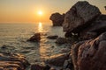 Reflection of the rising sun on the water surface of the sea during the dawn on the rocky shore