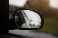 The reflection of road in the side view mirror with raindrops. Travel concept. Bad weather and grey sky Royalty Free Stock Photo