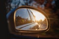 Reflection of the road in the sunset sunlight blurry in the side mirror of the car. Close-up Royalty Free Stock Photo