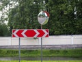 Road traffic mirrow and the red traffic sign with two directions for driving on the forest and river background Royalty Free Stock Photo