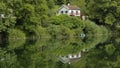 Reflection of a small rural house in water surface. Royalty Free Stock Photo