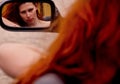 Reflection of a young redhead woman with wild red hair in the car mirror