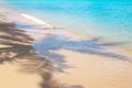 Reflection of a shadow from a palm tree on a sandy shore with an azure clear sea. Tropical background Royalty Free Stock Photo