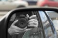 Reflection in side view mirror of someone with camera. Royalty Free Stock Photo