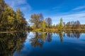 Reflection of small trees in a lake under a blue sky with intermittent clouds Royalty Free Stock Photo