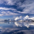 Reflection of a snow covered cliff in the water under the beautiful clouds in the sky in Norway Royalty Free Stock Photo