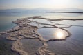 Reflection of the sun at dawn in the water of the Dead Sea with salt formations Royalty Free Stock Photo