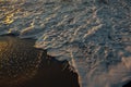 Reflection of the sun in the foamy surf during sunset on the ocean coast. Royalty Free Stock Photo