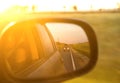 Reflection of sunny road and sunset at the car side mirrow. Royalty Free Stock Photo