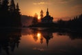 reflection of sunset on the lake and chapel in mountains, with silhouette of trees Royalty Free Stock Photo