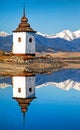 Reflection of tower of church on water surface of lake. Snowy mountains at background Royalty Free Stock Photo