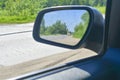 Reflection of traffic in the left rear-view mirror on a sunny day