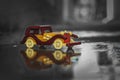 Reflection Vintage toy car under the rain on the road. Miniature Car Toy reflection in Rain. Reflection Red and yellow vintage car