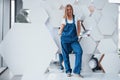 Reflection of wheel. Girl in blue uniform stands against abstract wall with white pieces of surface in the shape of