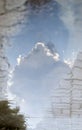 Reflection of white cloud and blue sky in puddle on paving slabs