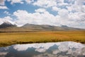 Reflection of white clouds in artificial reservoir of the Central Asian mountains. Sunny scene