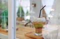 Reflection from window glass of Iced coffee with milk on wooden table at cafe Royalty Free Stock Photo