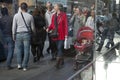 Reflection in the window. A woman is pushing a red stroller with a sleeping baby. People walk at Covent Garden.