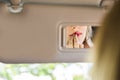 Reflection of woman painting her lips in car mirror