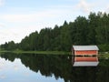 Reflection of a wooden cottage and the trees on a calm and tranquil lake captured in Finland Royalty Free Stock Photo