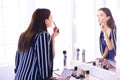 Reflection of young beautiful woman applying her make-up, looking in a mirror Royalty Free Stock Photo
