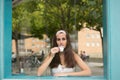 Reflection of young long-haired woman drinking an espresso behind the glass of a coffee shop. Royalty Free Stock Photo