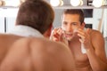 Reflection of young man in mirror applying shaving cream Royalty Free Stock Photo