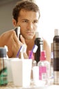 Reflection of young man in mirror shaving with electric shaver Royalty Free Stock Photo