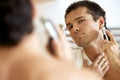 Reflection of young man in mirror shaving with electric shaver Royalty Free Stock Photo