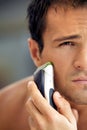 Reflection of young man in mirror shaving with electric shaver Royalty Free Stock Photo