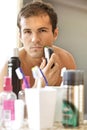 Reflection of young man in mirror shaving with electric shaver Royalty Free Stock Photo