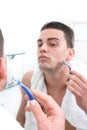 Reflection of young man shaving in bathroom mirror Royalty Free Stock Photo