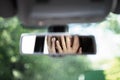 Reflection of young woman with frightened eyes covering her face with  hands in the car rear view mirror. Concept of an accident o Royalty Free Stock Photo