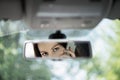 Reflection of young woman talking on a mobile phone in the car rear view mirror. No cell phone, while driving Royalty Free Stock Photo