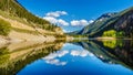 Reflections of blue sky, trees and mountains in the smooth surface on the crystal clear water of Crown Lake Royalty Free Stock Photo